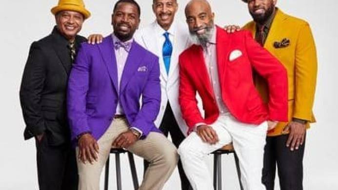 A group of Black men in a variety of bright colored suits.